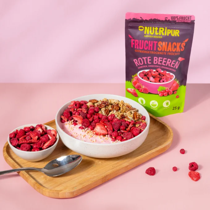 Hier ist ein Bild mit dem Nutripur Rote-Beeren-Mix mit Müsli und Joghurt in einer Müslischale. Im Hintergrund ist die Verpackung abgebildet.